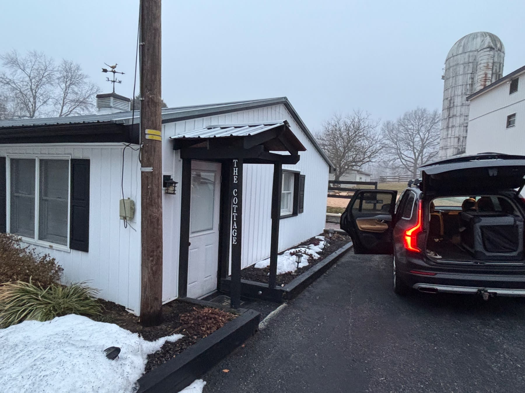 Tree Cottage roadside shop with white exterior, black trim, and red vehicle parked outside on a rural property.