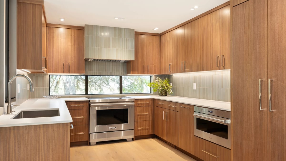 Walnut kitchen with full-height cabinetry, a stainless range and a horizontal window strip in place of a backsplash