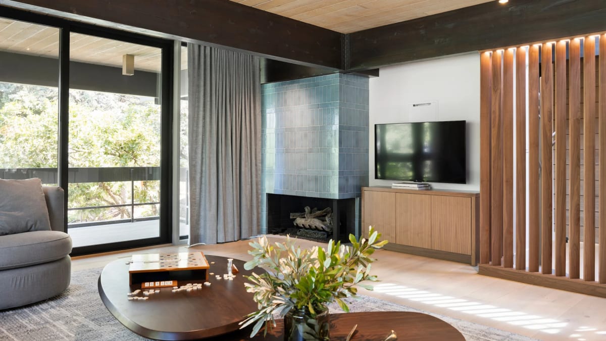 Fireplace with a blue-green tile surround beside a wall-mounted television and vertical wood slat screen