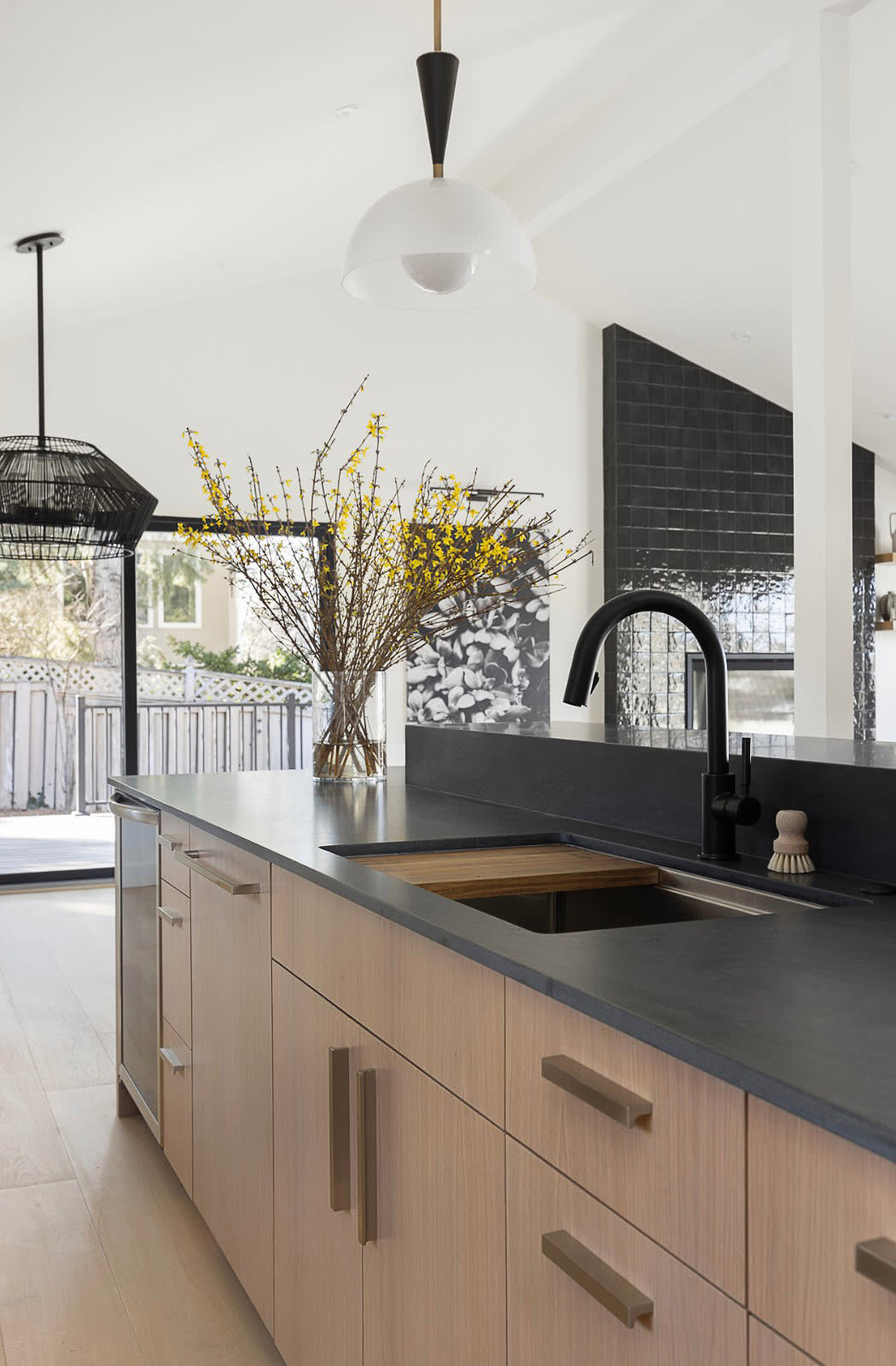 Kitchen island in white oak with a honed black counter, matte black faucet and undermount sink