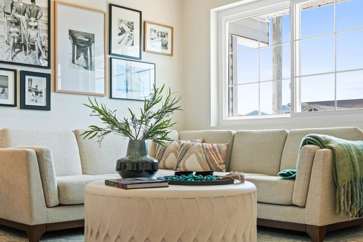 Cream sectional layered with a striped pillow and teal throw around a round pleated ottoman