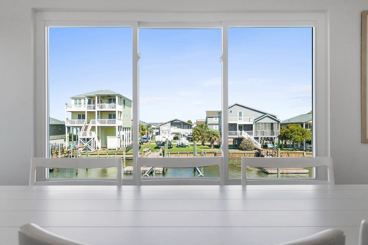 View from the dining table through a picture window to pastel beach houses across the waterway