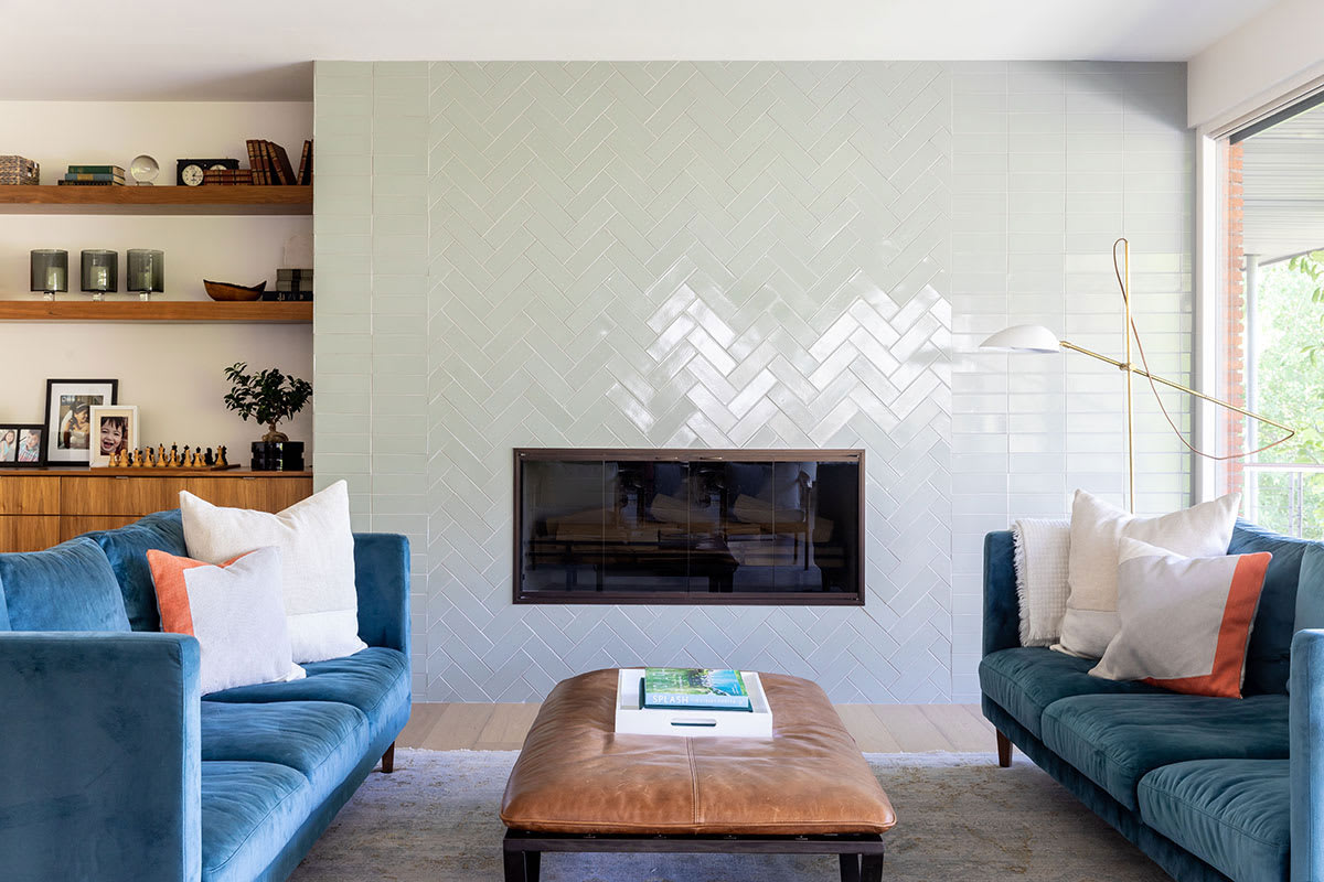 Bright and airy living room remodel with herringbone tiles around gas fireplace.