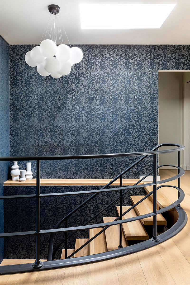 Sweeping stairway leading to lower level with bright skylight.