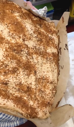 Cooked roulade being turned out onto baking parchment on a work surface.