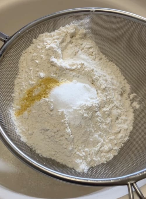 Flour, baking powder, salt and dry mustard powder, and add a good grinding of black pepper being sieved into a bowl.