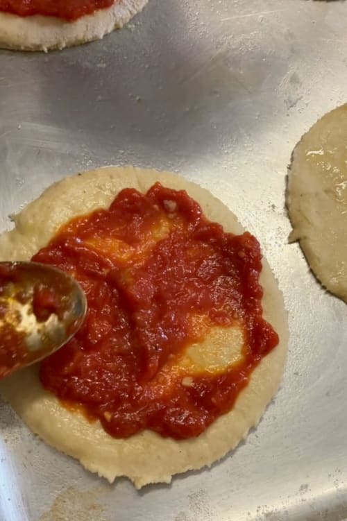 Tomato sauce spread onto each pizza.
