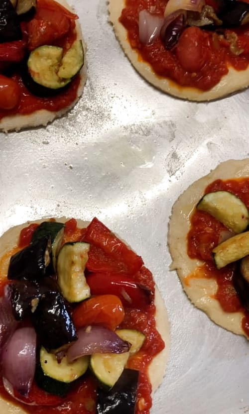 Roasted vegetables placed on top of pizzas.