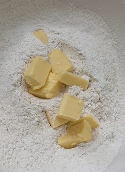 Small pieces of butter on top of flour mixture
