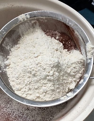 Flour mixture being sieved into a bowl