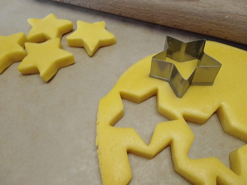 Metal star cutter on top of rolled out marzipan with some cut out stars of marzipan