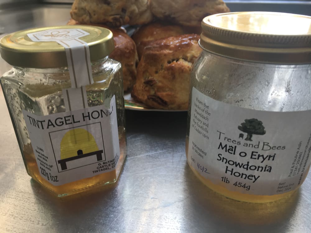 Jars of nearly empty honey with plate of fig and honey scones in the background