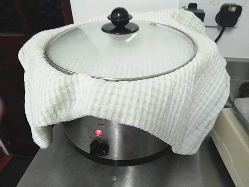 Slow cooker with tea towel under the lid