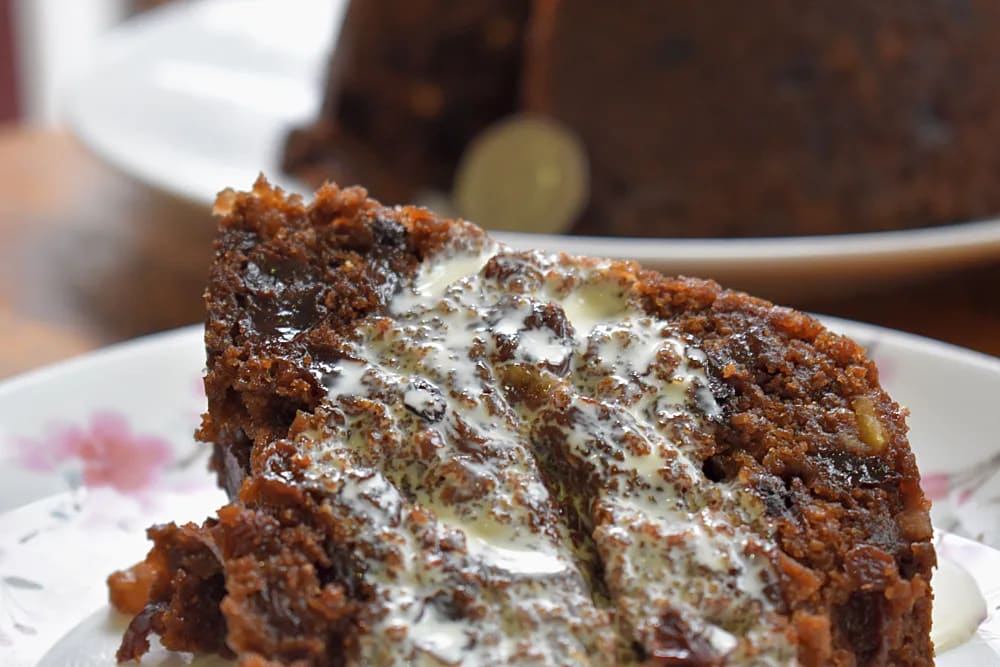 Halloween Pudding slice on a plate served with cream and whole pudding in background