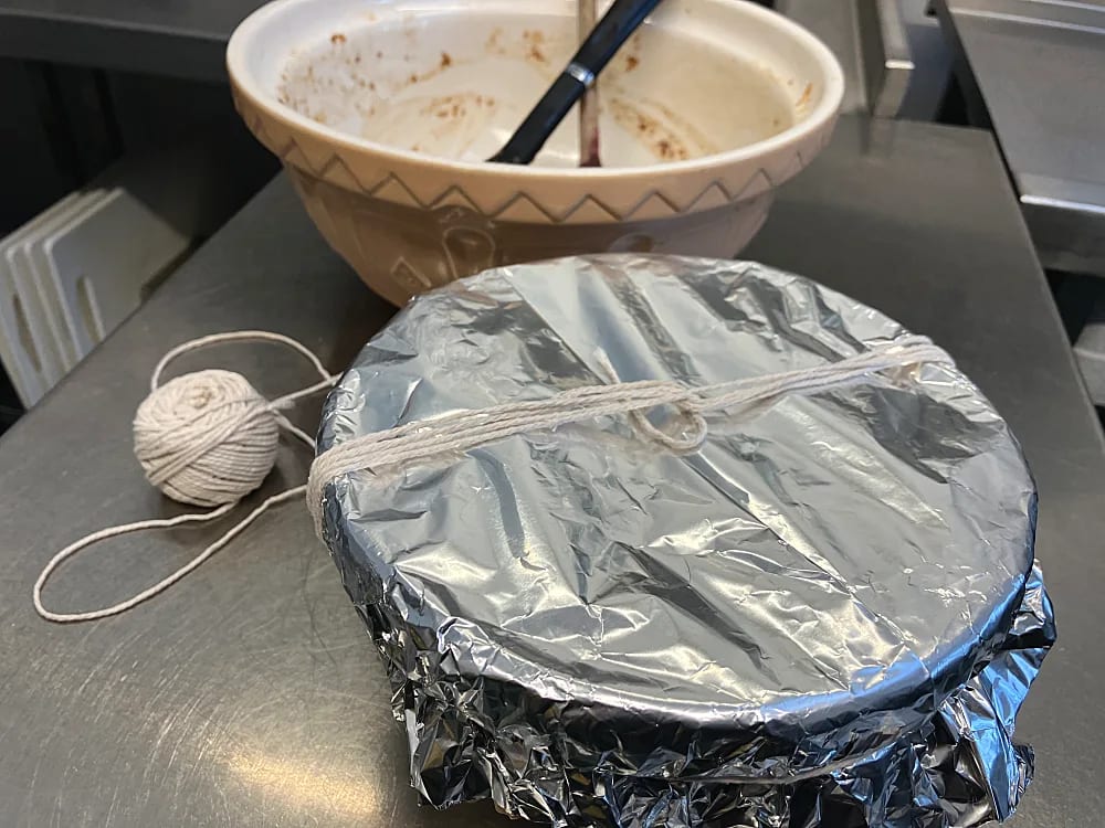Christmas Pudding in bowl covered with foil and with string tied to make a handle