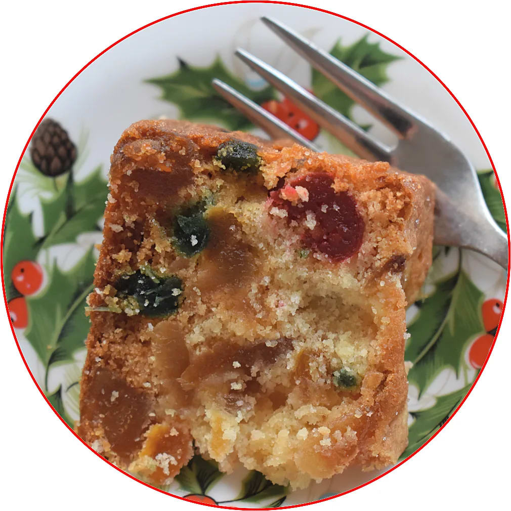 Slice of Glace Fruit Christmas Cake on a holly and red berry decorated plate