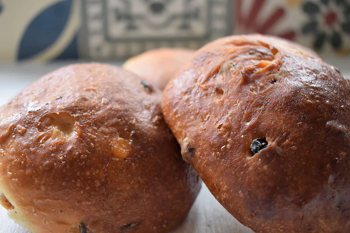 Currant buns close up showing dried fruits with patterned tiles in the background