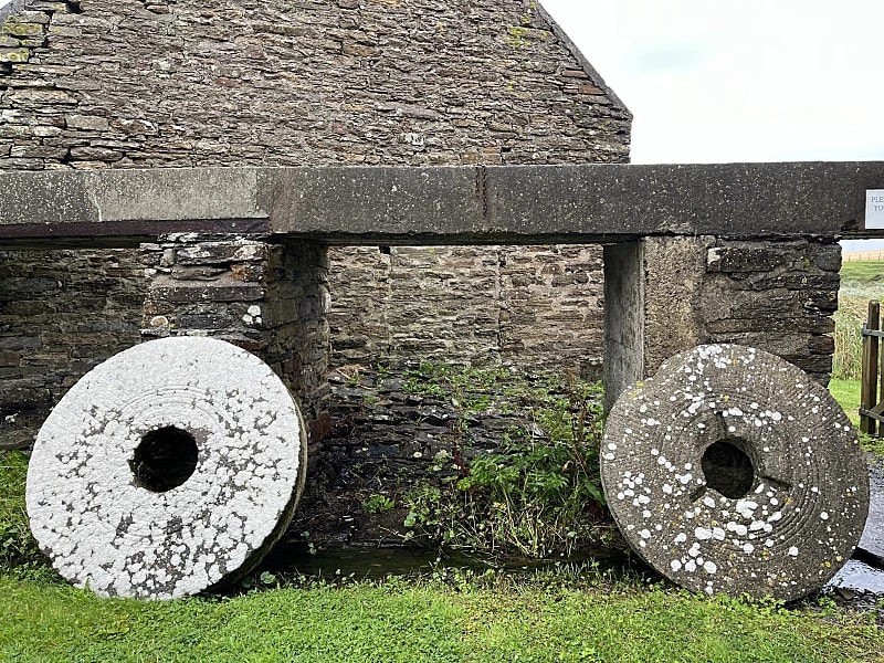 Outside Barony Mill with two old grinding stones leant up against the outside of the side of the building