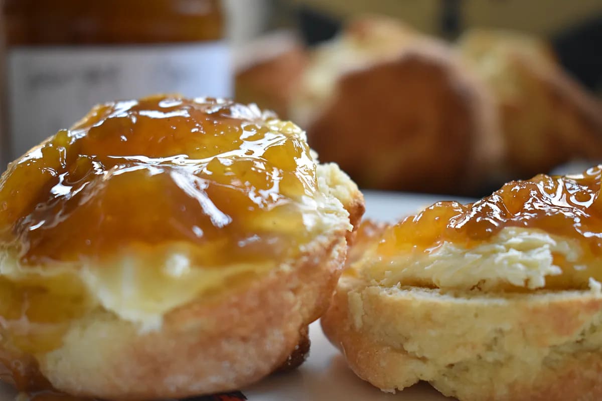 Gluten Free Scones served with clotted cream and greengage jame with jam jar in the background.