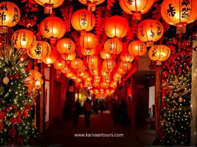 Street in Yokohama Chinatown lined with glowing red lanterns overhead and people walking below at night