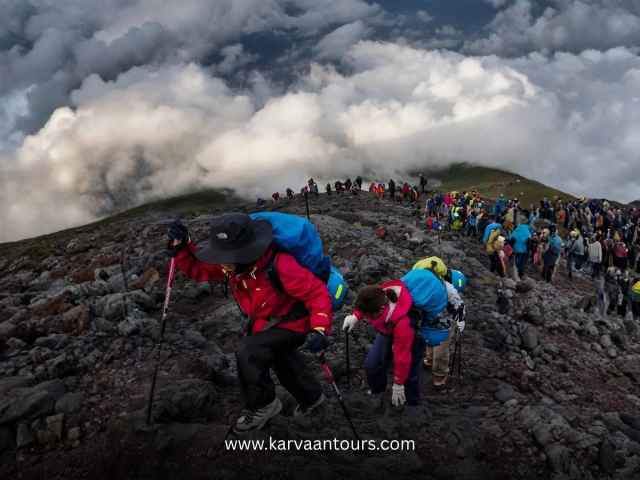 Hikers ascending a rocky slope with Mt Fuji above