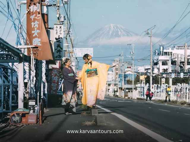 Woman in kimono with red umbrella walking toward Mt Fuji in snow