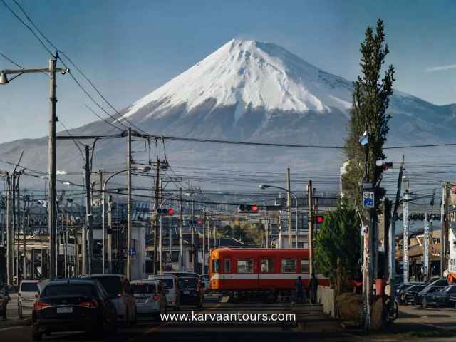 Orange train crossing in front of Mount Fuji in a city street
