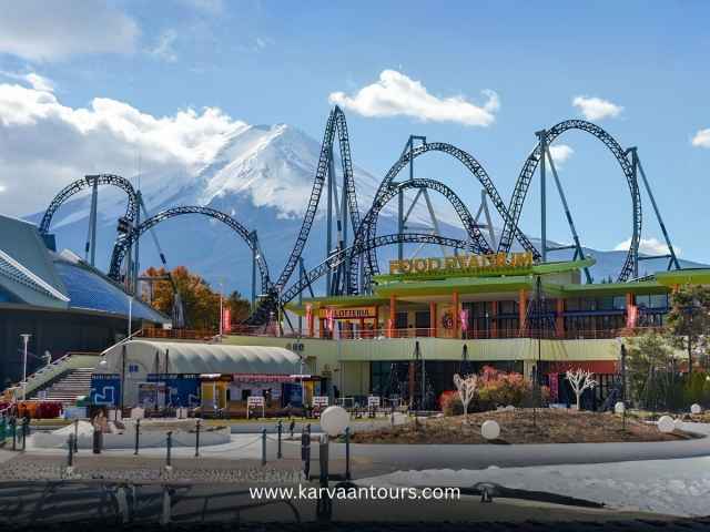 Breathtaking view of Mount Fuji behind the high-speed roller coasters at Fuji-Q Highland amusement park in Japan.