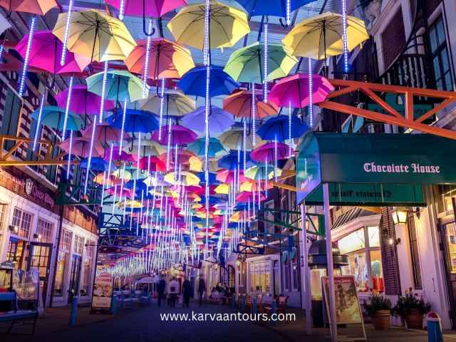 The Umbrella Street at Huis Ten Bosch theme park in Nagasaki illuminated with glowing neon lights at night.