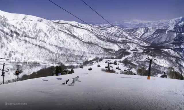 Wide view of a ski slope dotted with chairlift towers under a clear blue winter sky.