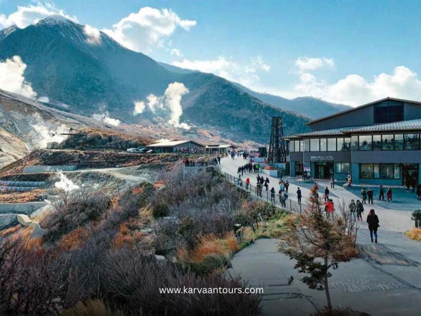 Tourists walking through Owakudani Valley in Hakone with visible volcanic steam vents and rugged mountain landscape