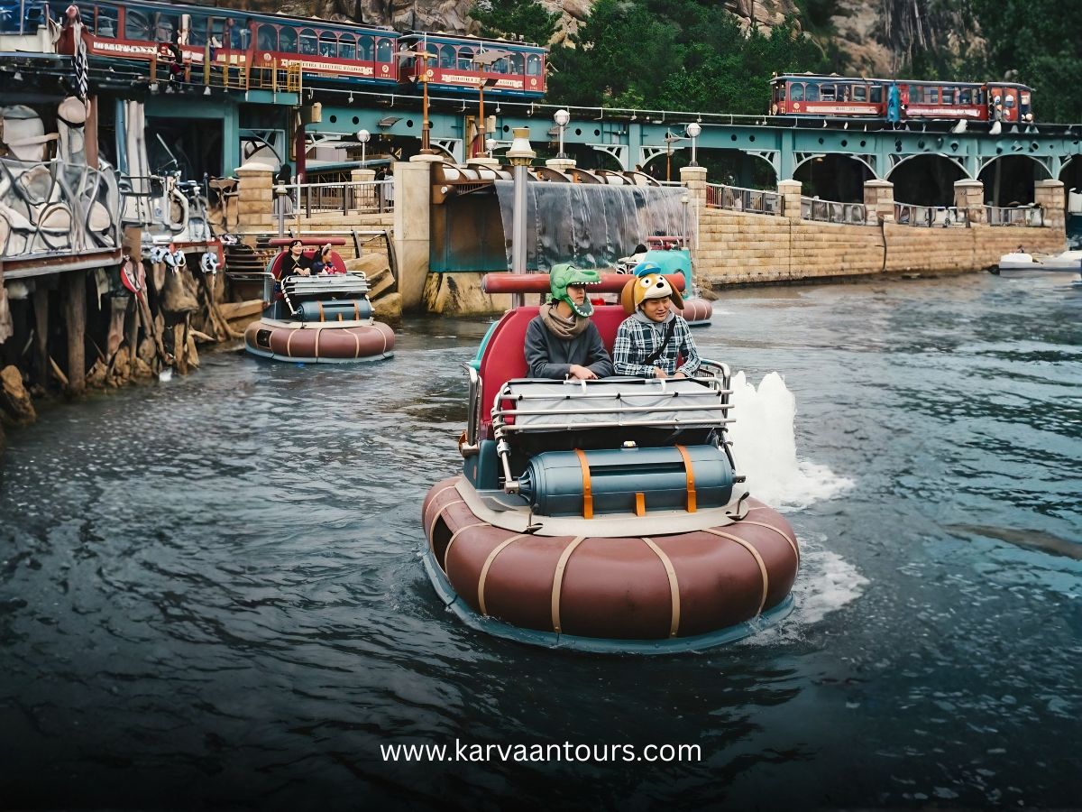 Tourists enjoying the Aquatopia water ride at Tokyo DisneySea with the electric railway passing in the background.