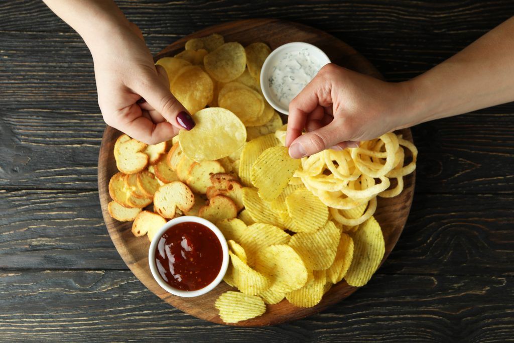 female-hands-hold-chips-over-the-tray-with-chips-t-C4AEMAK-1024x683.jpg