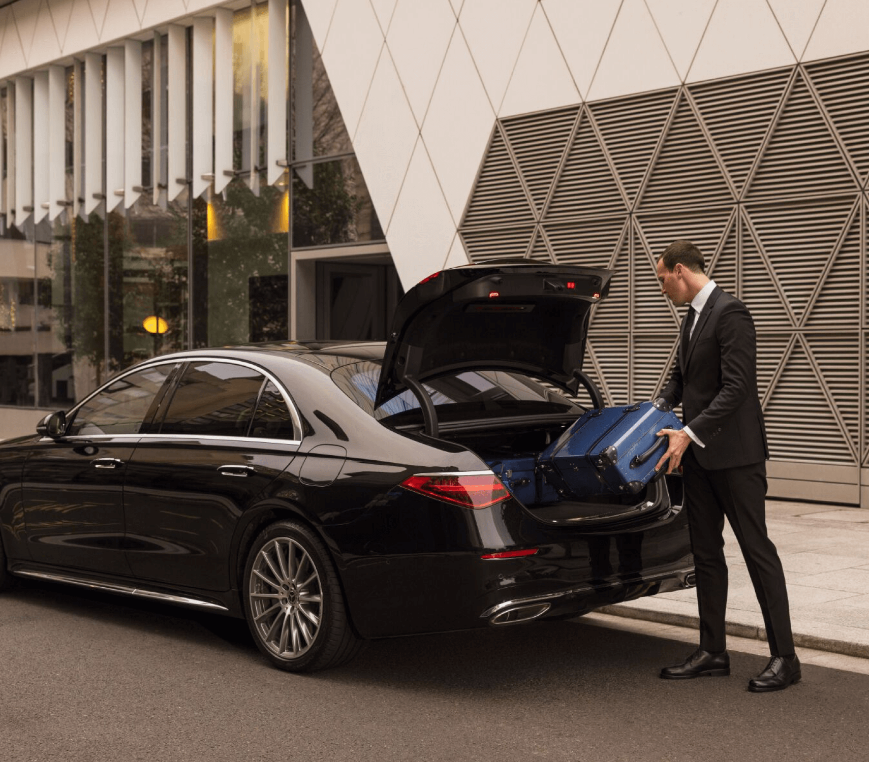Professional driver loading suitcases into a private rental car