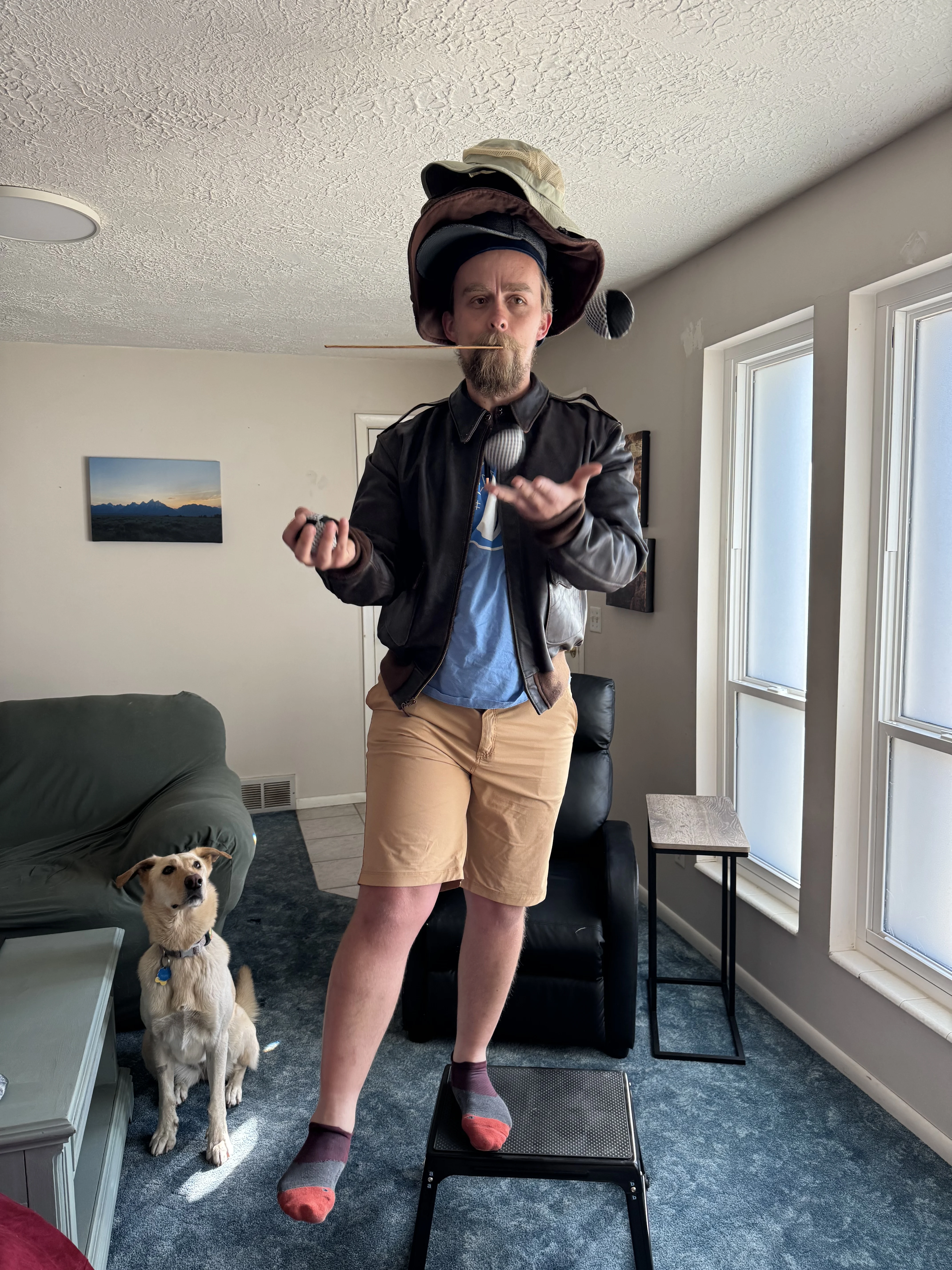 A man tries to wear many hats, juggle, and balance on a step.