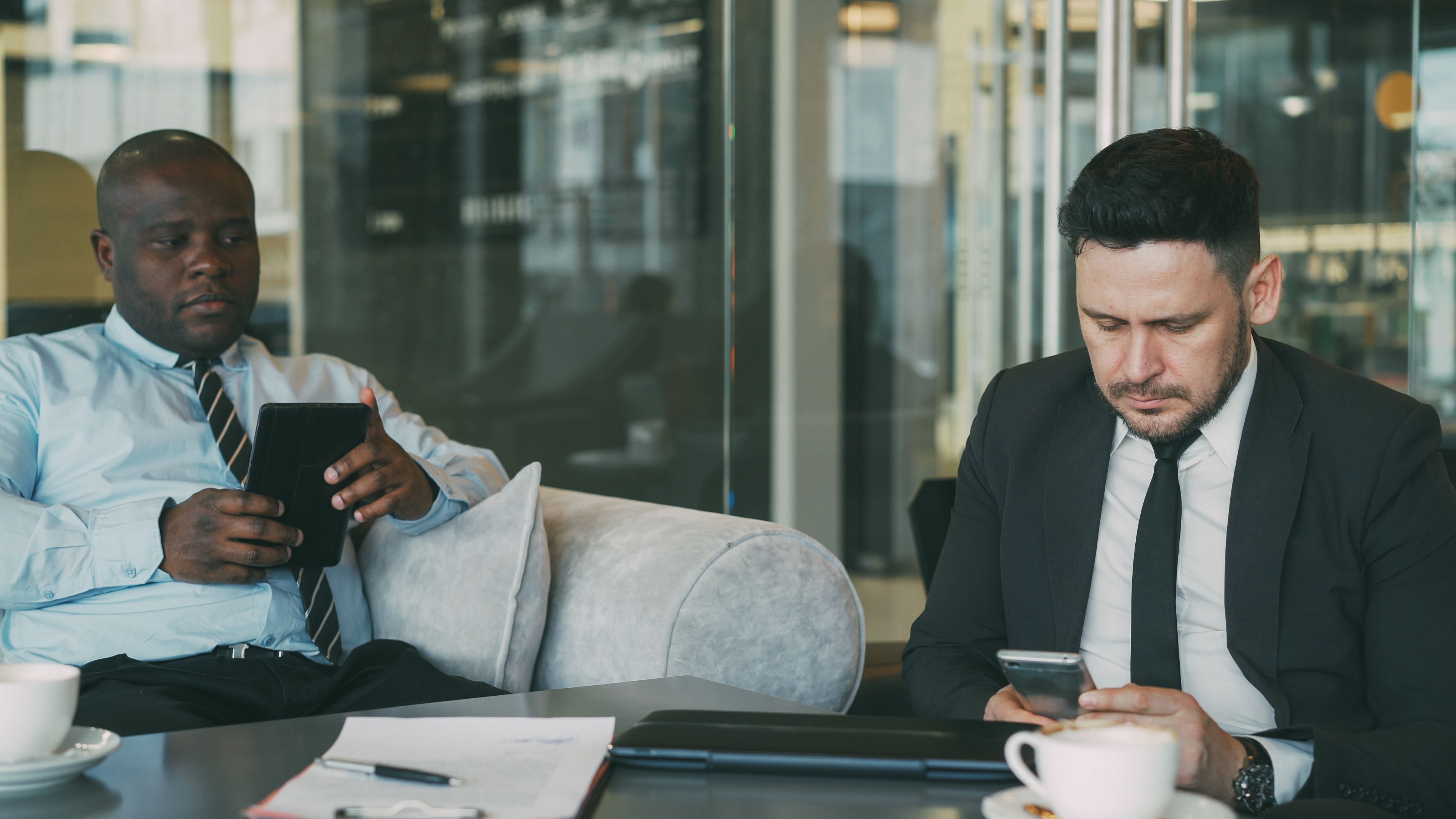 Two business professionals using mobile devices in an office, highlighting the importance of guest Wi-Fi security, business network protection, and cybersecurity for Northern Kentucky small businesses.
