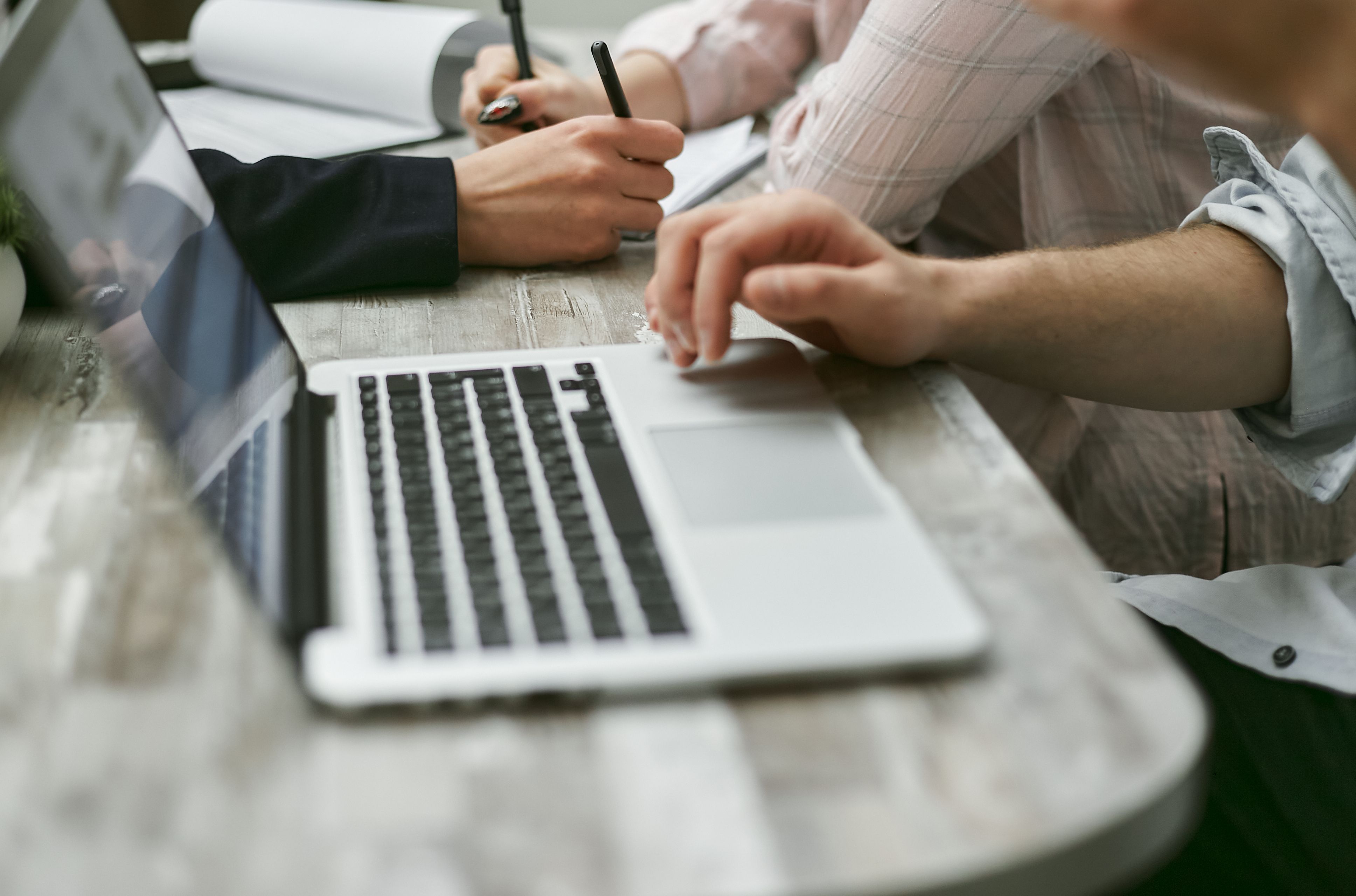Employees collaborating around a laptop in an office, highlighting the importance of managing employee administrator access and business computer security.