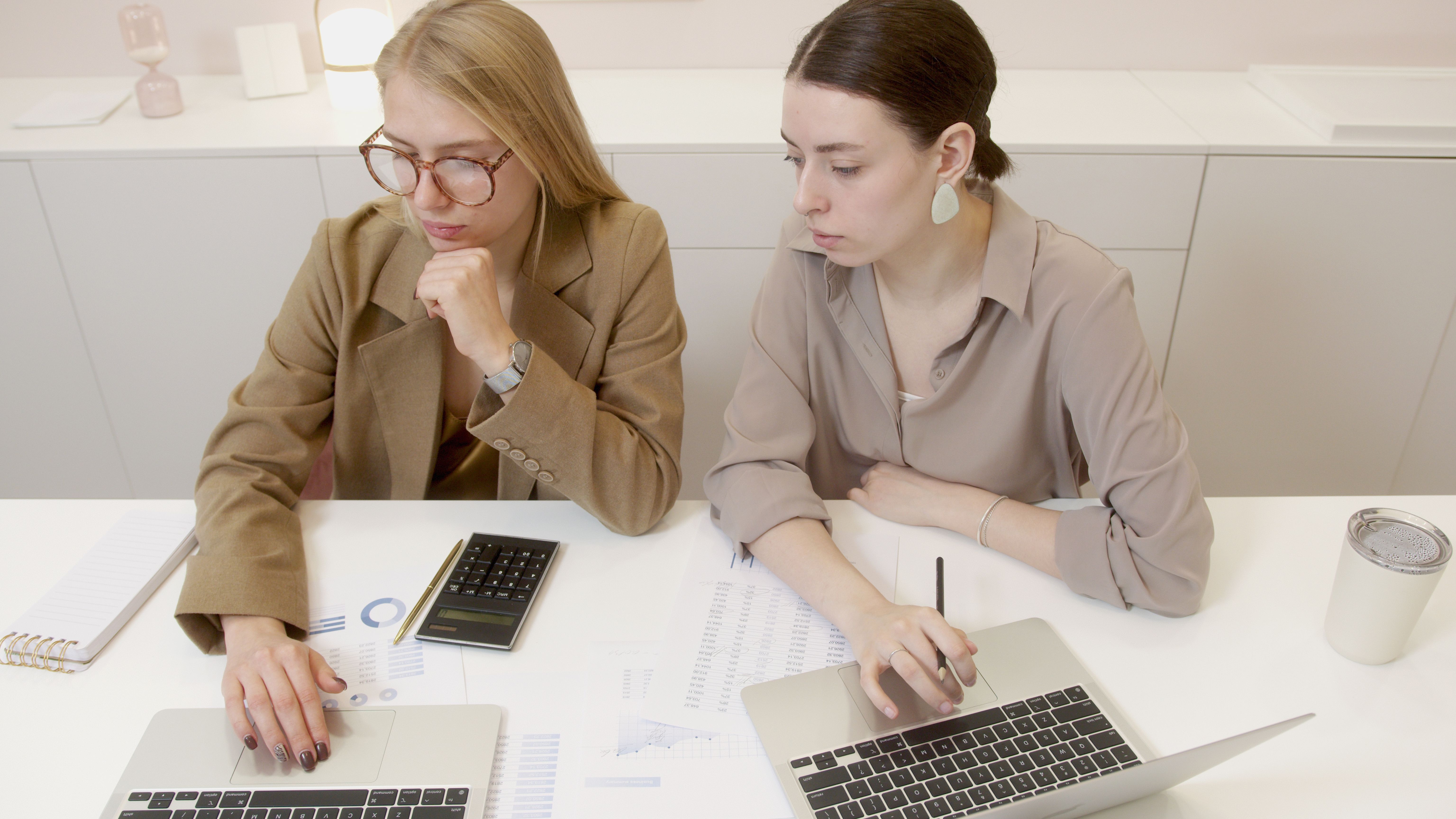 Two small business professionals reviewing financial reports and using laptops to plan an IT budget for businesses in Cincinnati and Northern Kentucky.