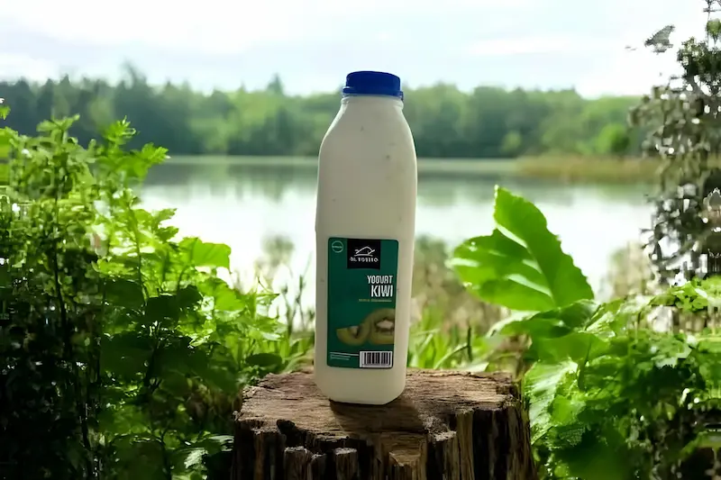 Yogurt de Kiwi encima de un tronco de madera con un lago de fondo y hojas verdes