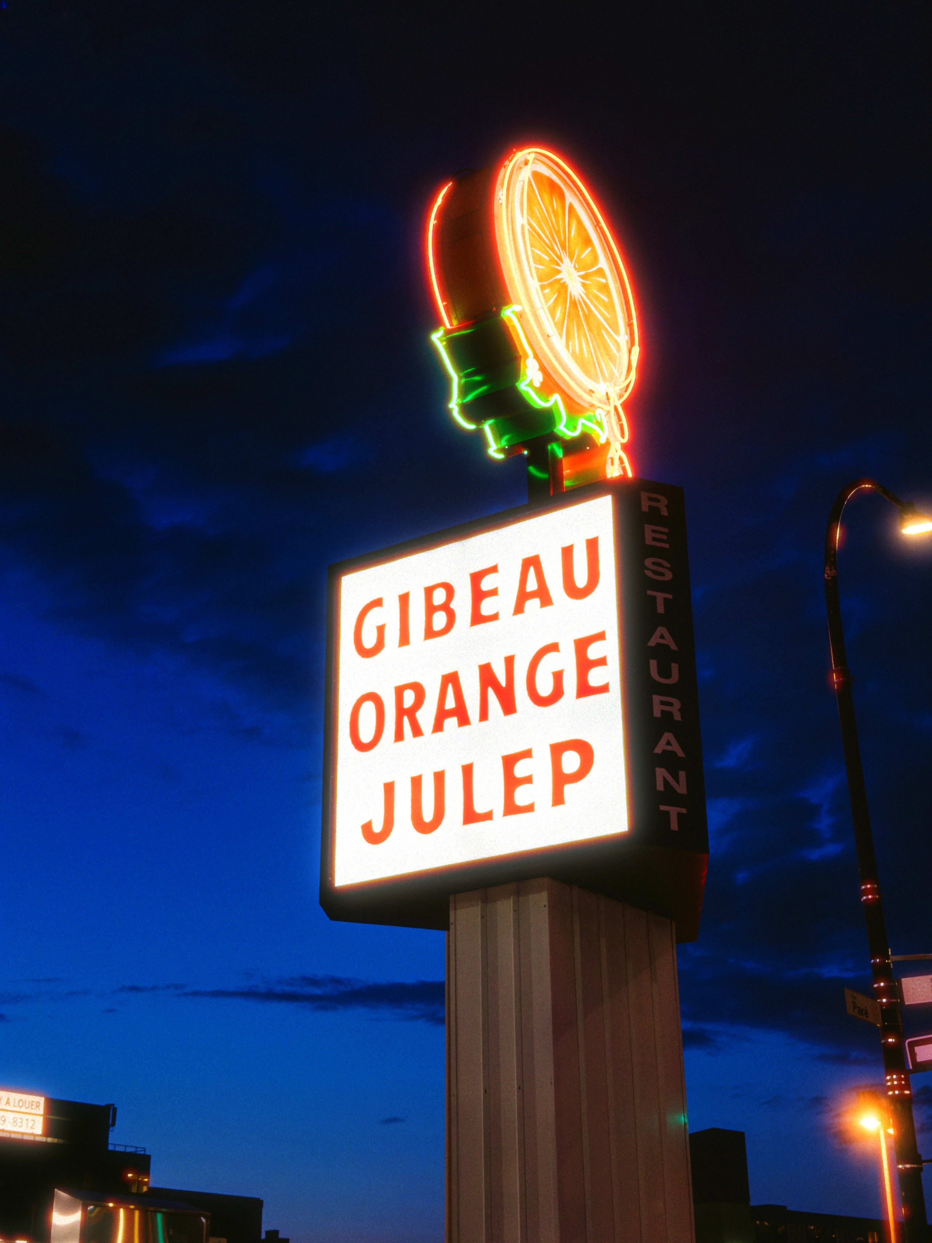 A Neon sign for the Gibeau Orange Julep, featuring a juicy orange slice on top.