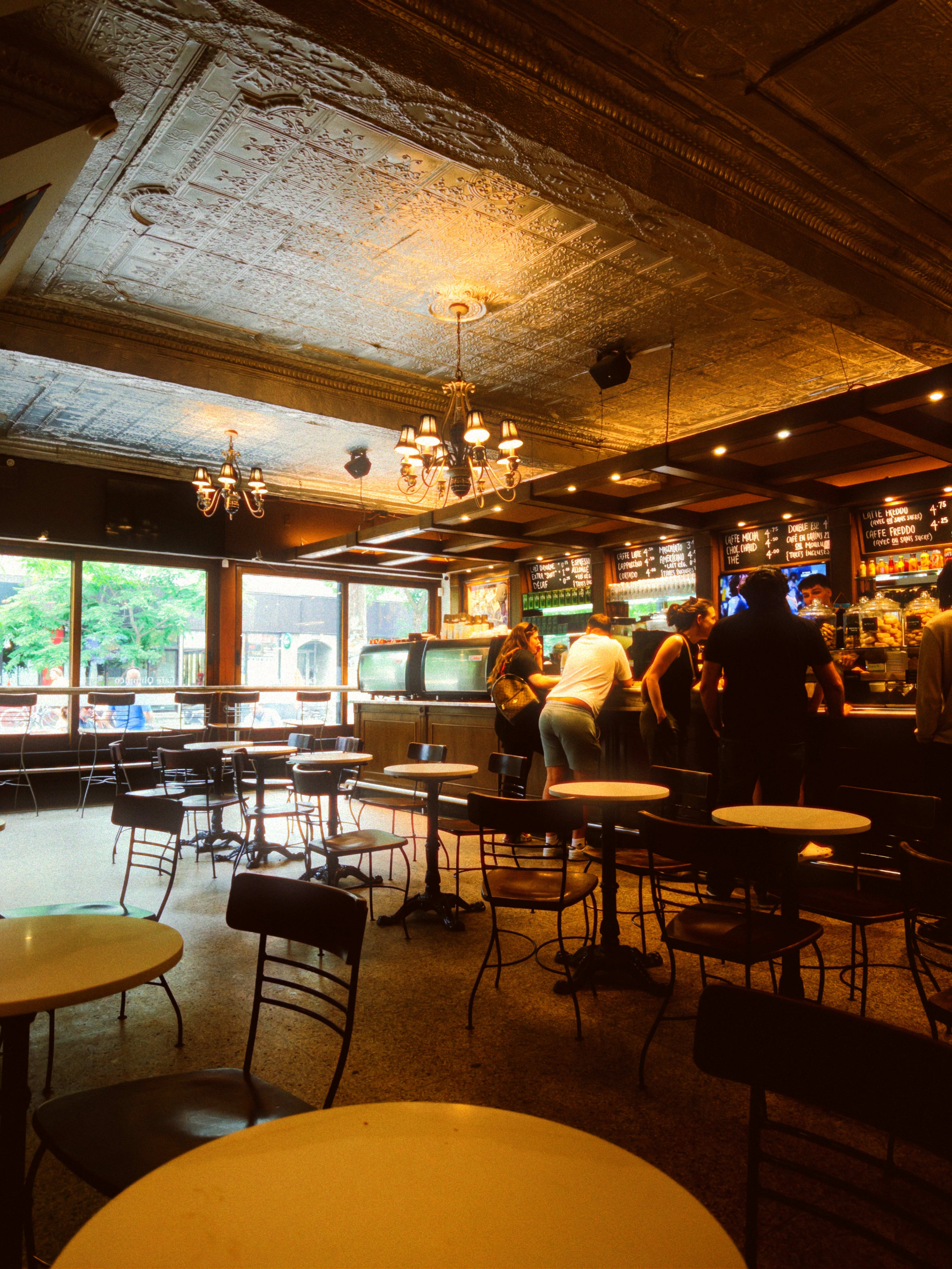 The interior of Cafe Olympico, with multiple patrons waiting on their coffee at the bar.