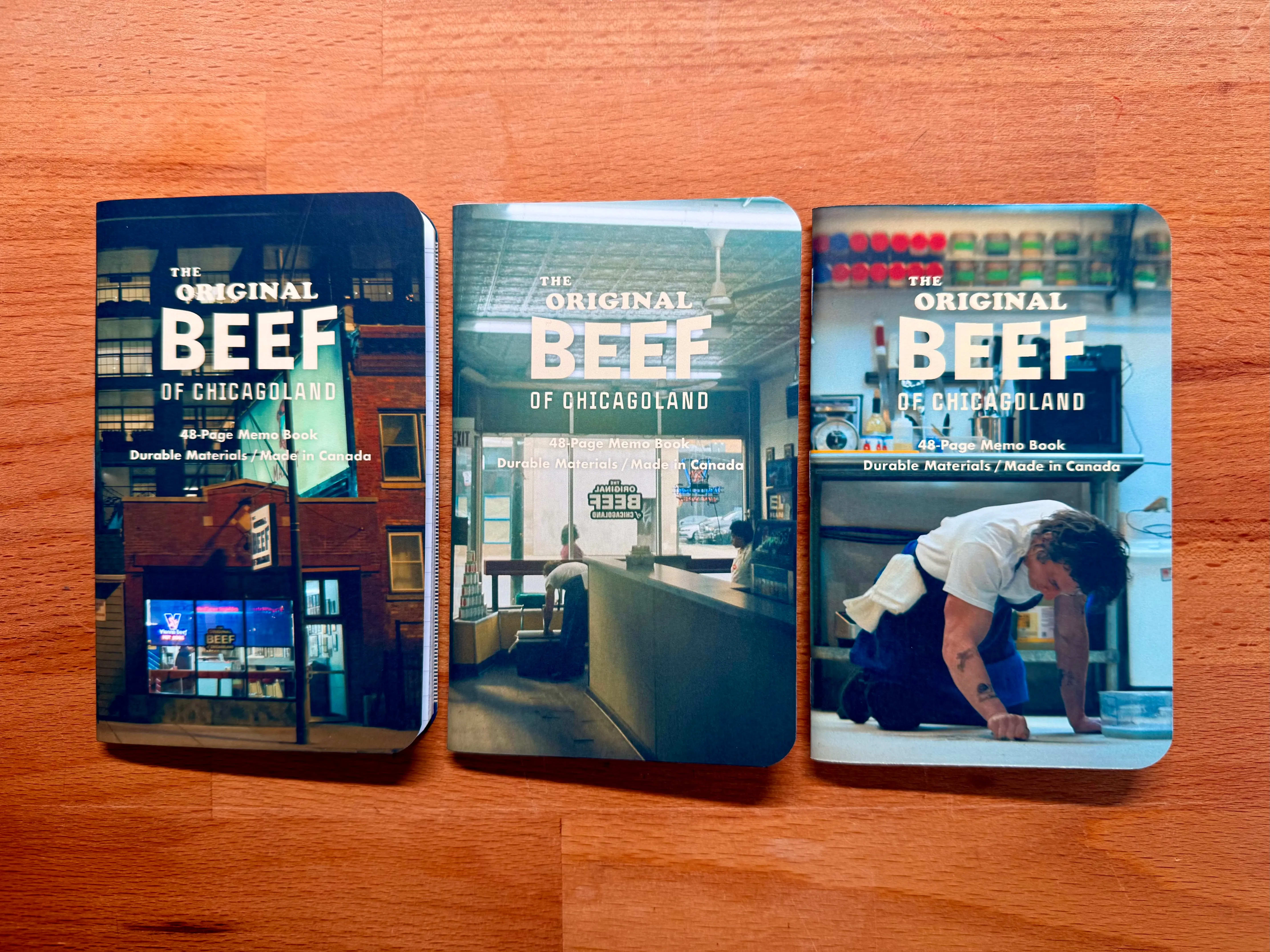 Three Mikie Notes notebooks displayed on a wooden desk, featuring various scenes from season one of the Bear.