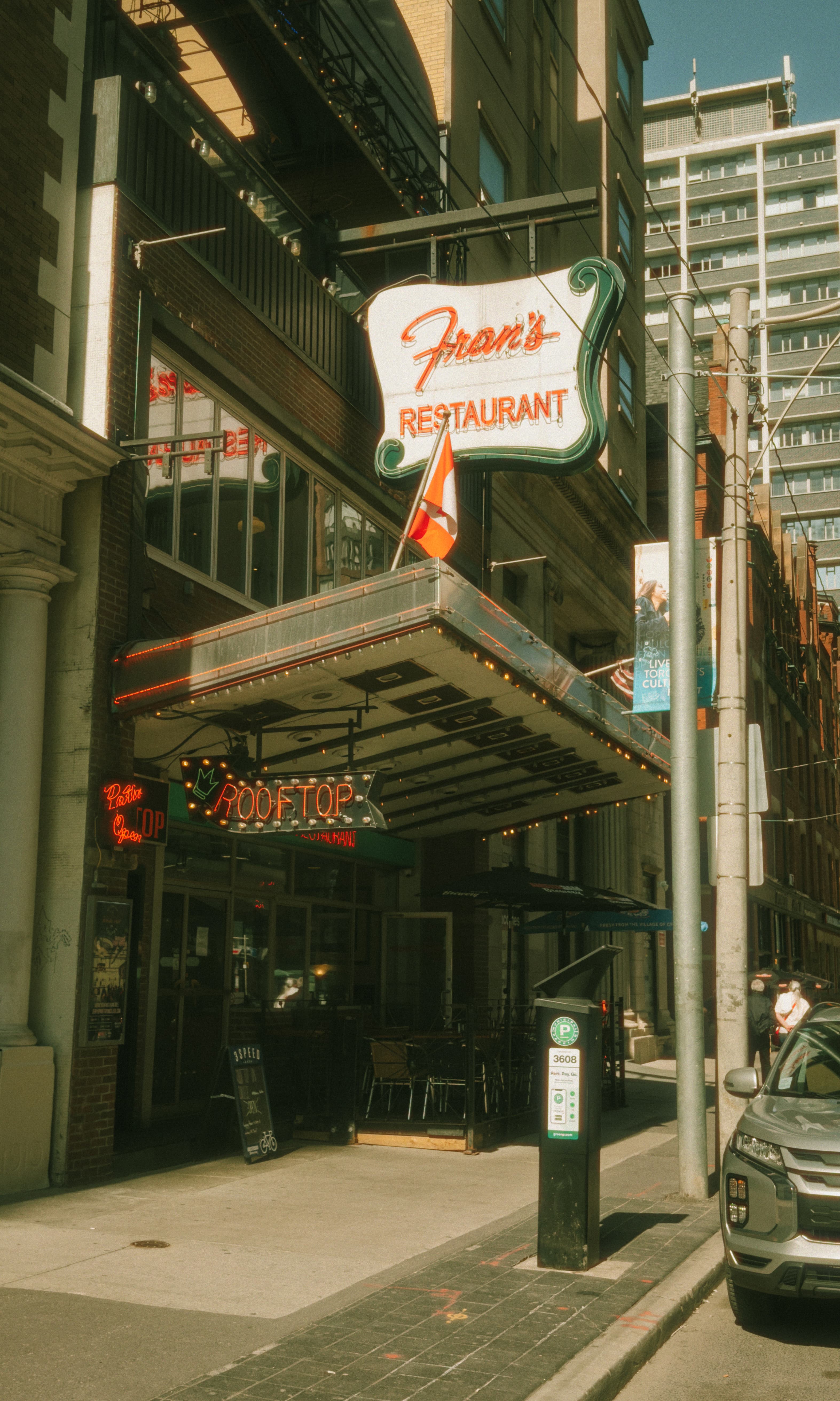 A photo of the exterior of Fran's Diner at College & Yonge in Toronto. It is a warm, sunny day with a clear sky.