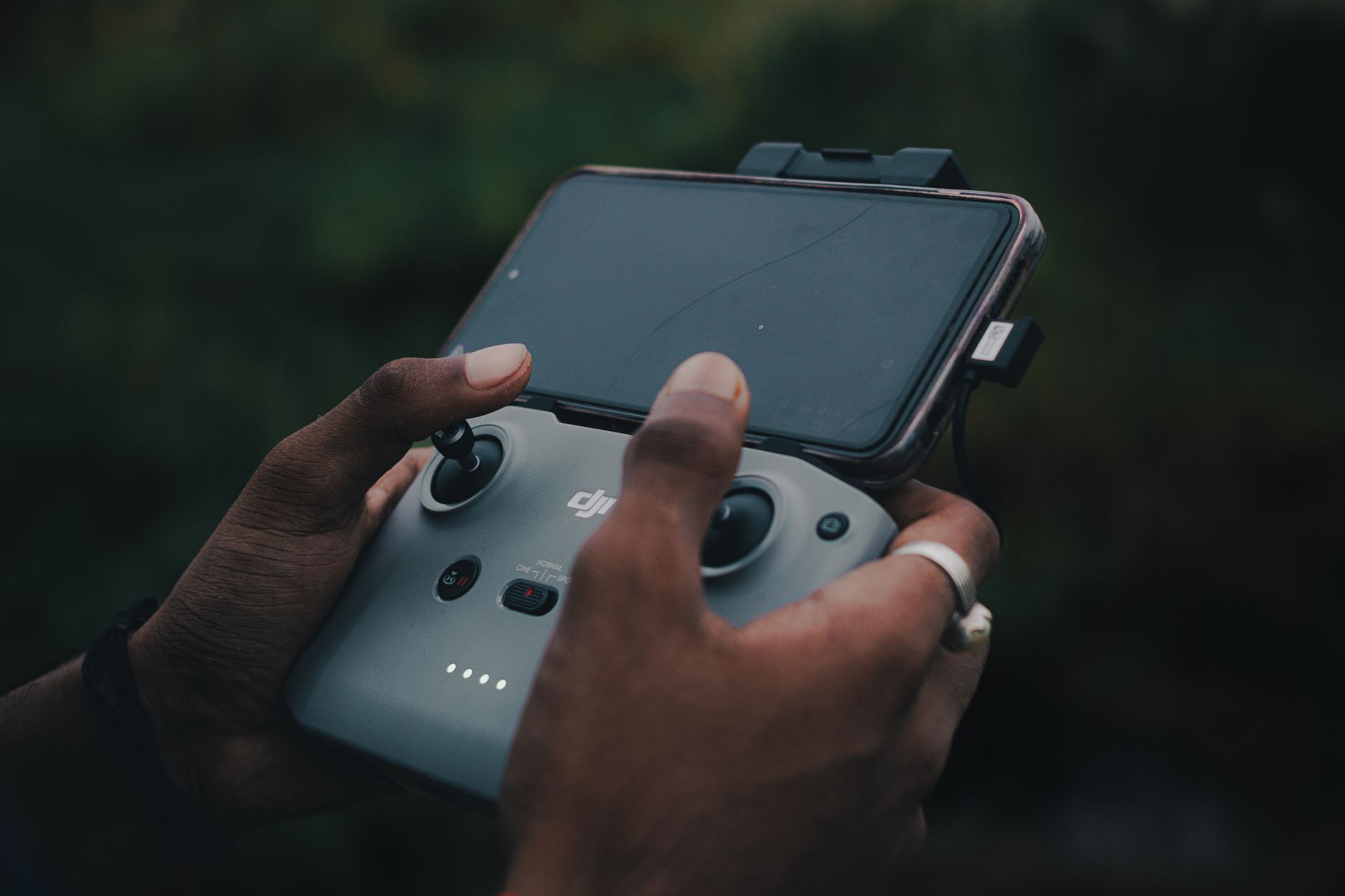 Hands holding a drone controller with smartphone attached, outdoors. Source: pexels.com (Aritra Hazra)