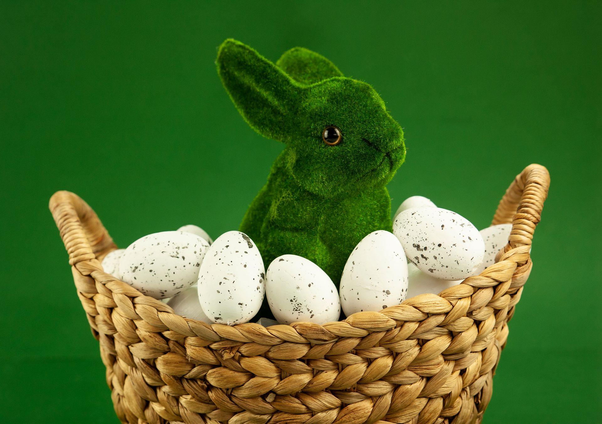 Green bunny figurine amid speckled white eggs in a woven basket. Perfect for Easter celebrations. Source: pexels.com (Karen Laårk Boshoff)