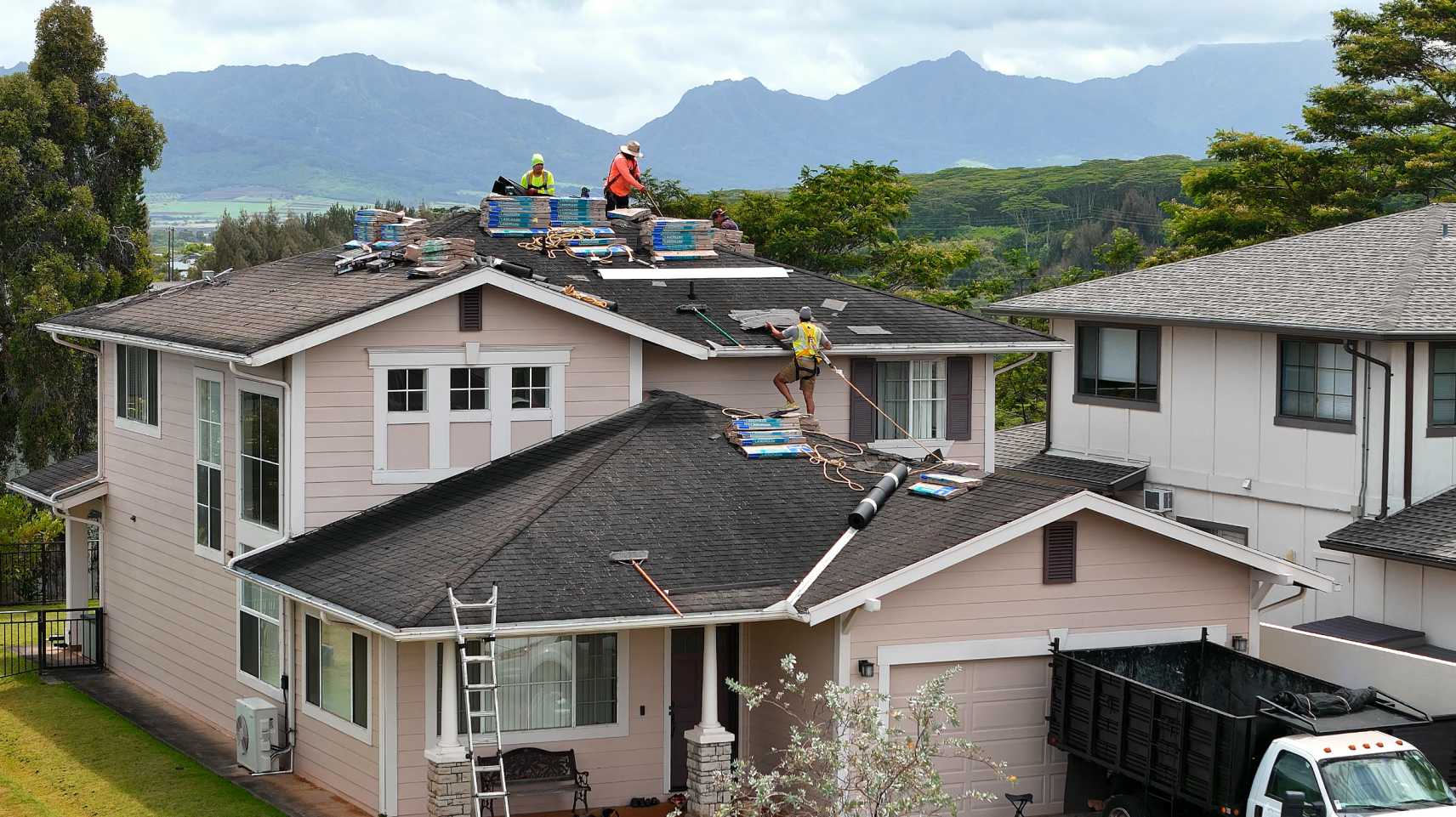 Drone roof-inspection photo of a re-roof in progress on Oahu, licensed roofers installing new shingles with the Ko&lsquo;olau range behind