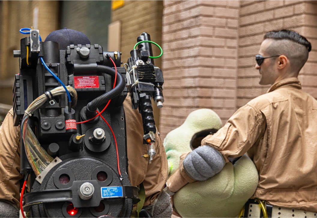 Ghostbuster cosplayers walking through the streets of New York with a proton pack and puppet Slimer.