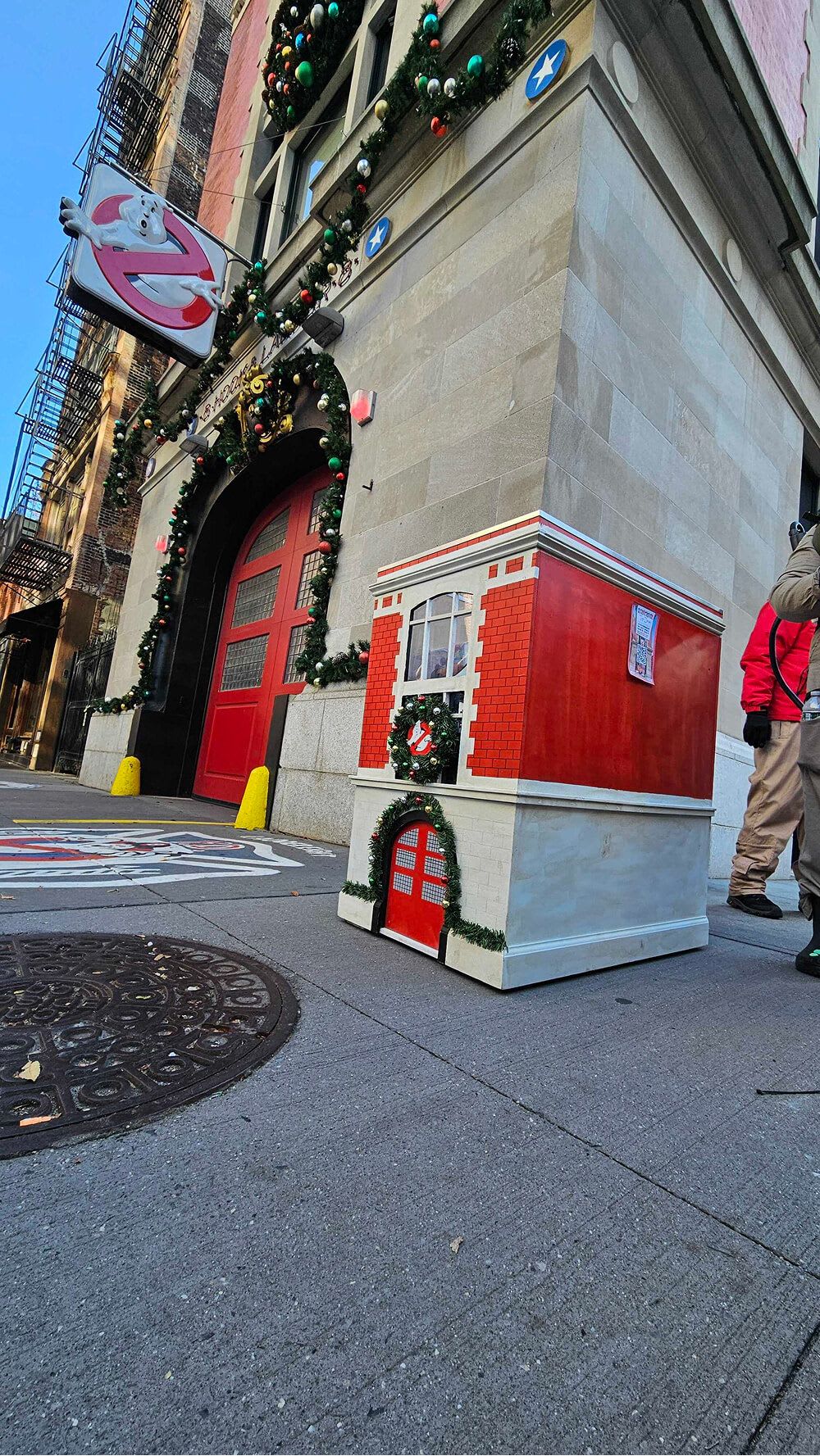 A miniature Hook & Ladder 8 toy drive collection box next to the authentic Ghostbusters HQ