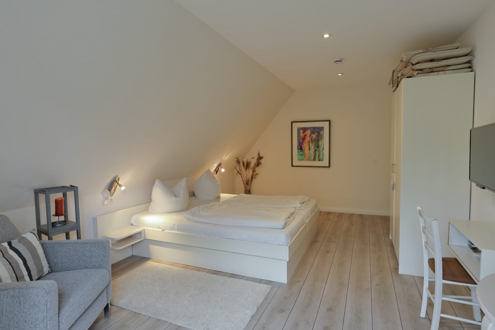 Schlafzimmer mit Doppelbett, kleinem Schreibtisch, Fernseher und großem Kleiderschrank