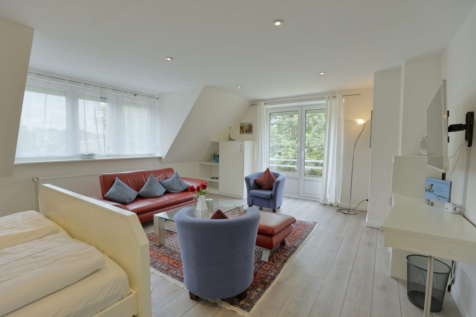 Wohnzimmer mit Doppelbett, einer Couch und 2 Sesseln